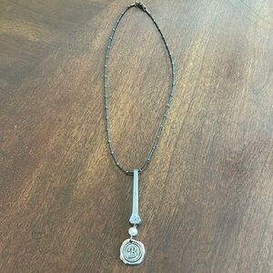 Black necklace with a “B” initial. Made by local artisan.